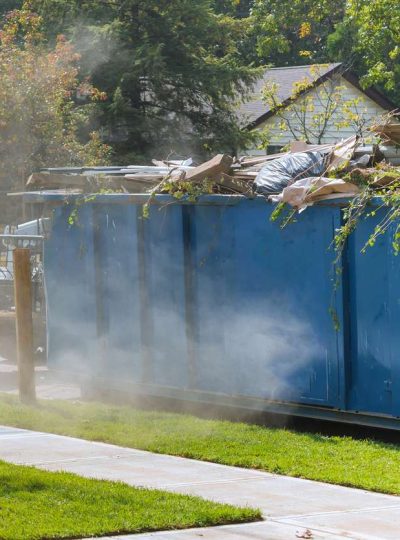 Lawn grass in rolls on pallets against of the street the rolled grass lawn ready for laying and loaded dumpster near construction urban landscape design